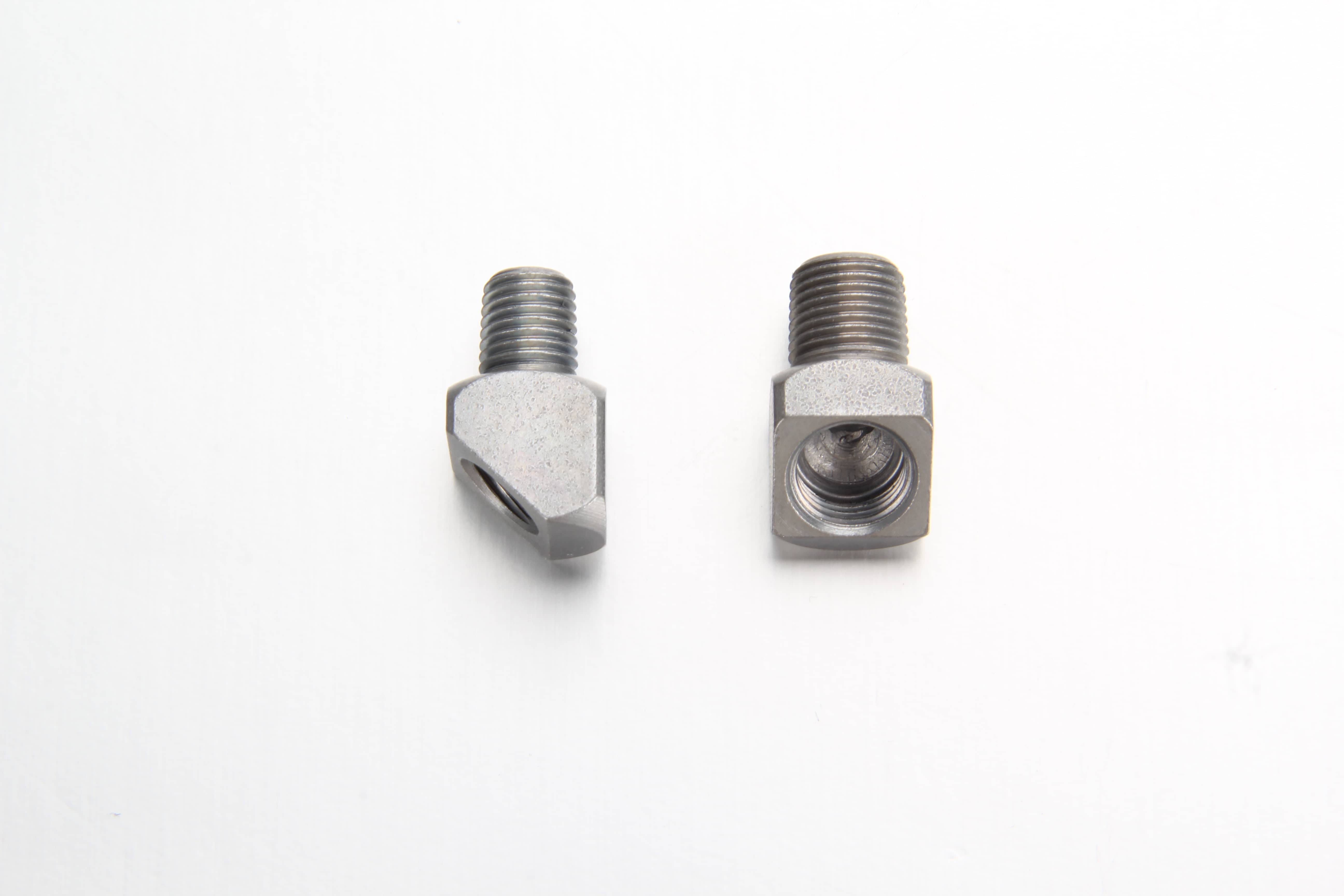 A 45 degree male-to-female thread lube adapter installed onto a centralized progressive distributor block routing flexible nylon tubing in a tight space.