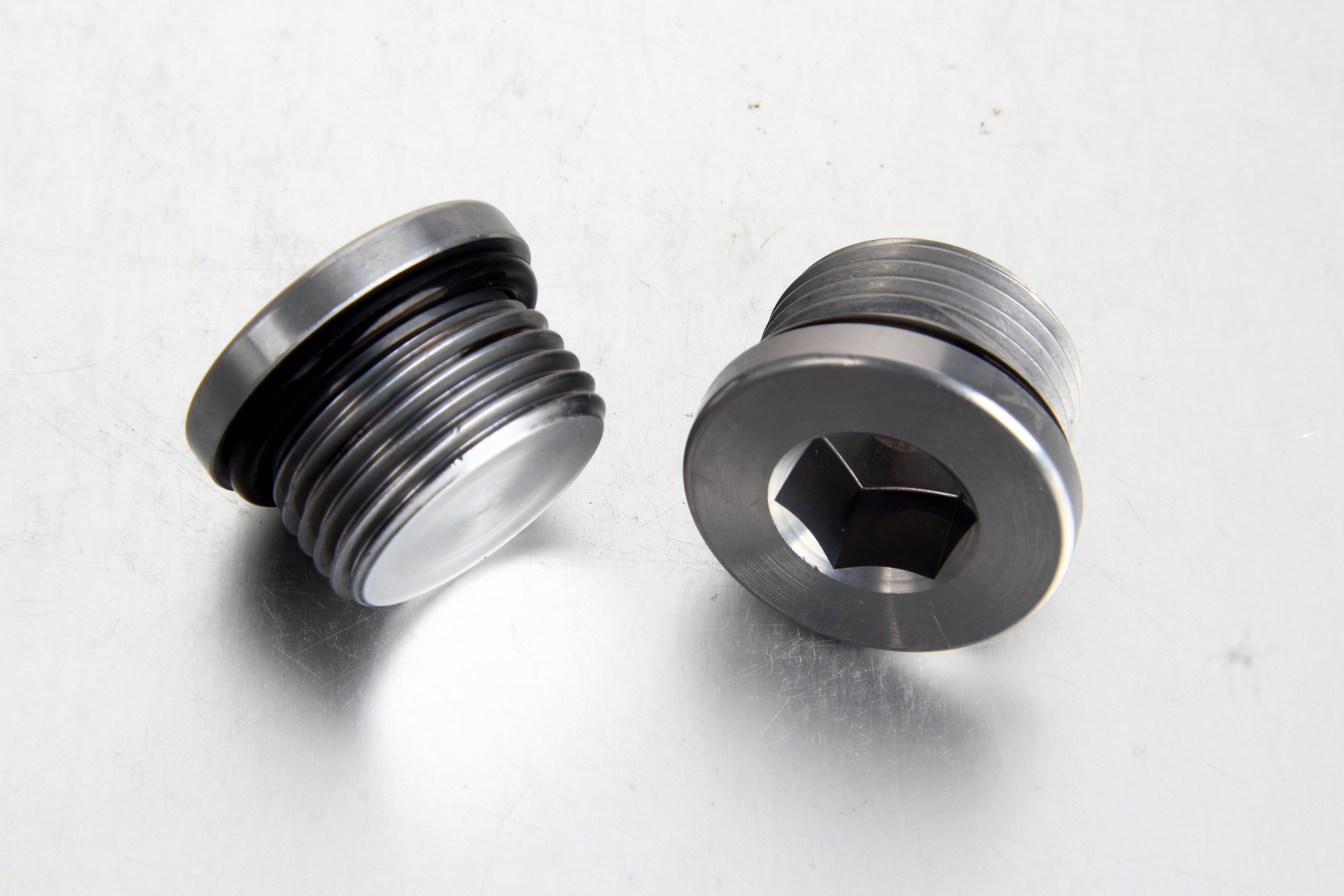 A crisp studio shot of a steel DIN 908 internal hexagon socket screw plug showcasing its precision groove and embedded green/black ED soft sealing NBR ring.
