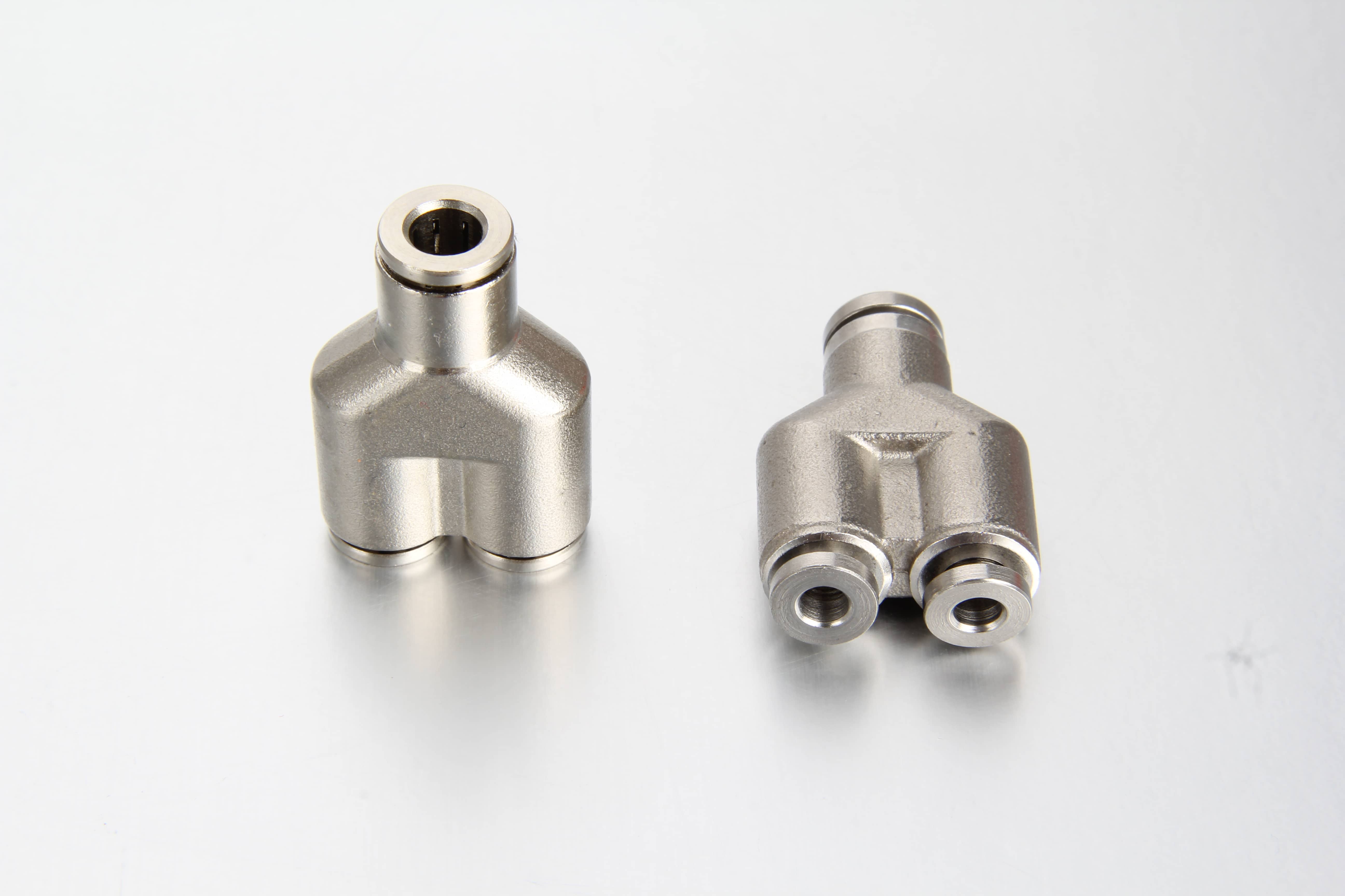 A high-pressure quick-connect Y union coupling installed on a progressive metering valve block, splitting 6mm nylon grease lines.